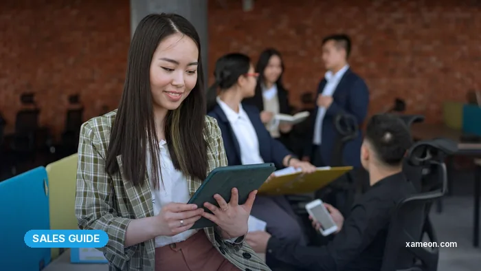 Saleswoman reviewing a quotation on a tablet with colleagues nearby.