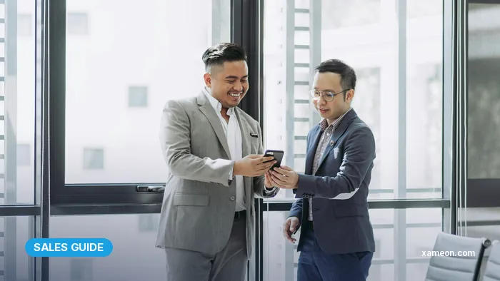 Two Malaysian businessmen reviewing a customer account on a phone in a meeting room.