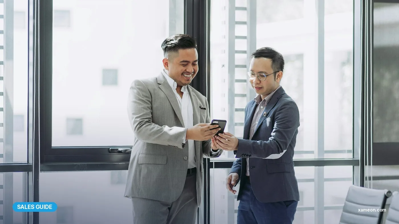 Two Malaysian businessmen reviewing a customer account on a phone in a meeting room.